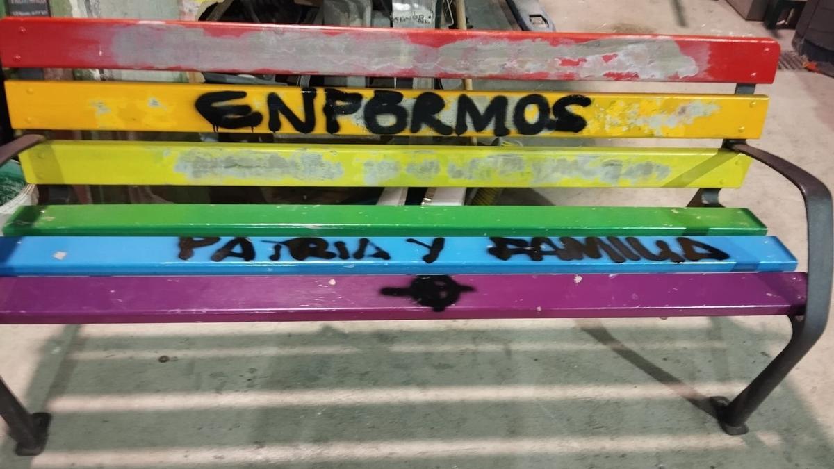 Banco público decorado con los colores de la bandera arcoiris vandalizado.