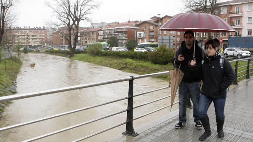 Dos jóvenes caminan por encima del río Gobela en Getxo