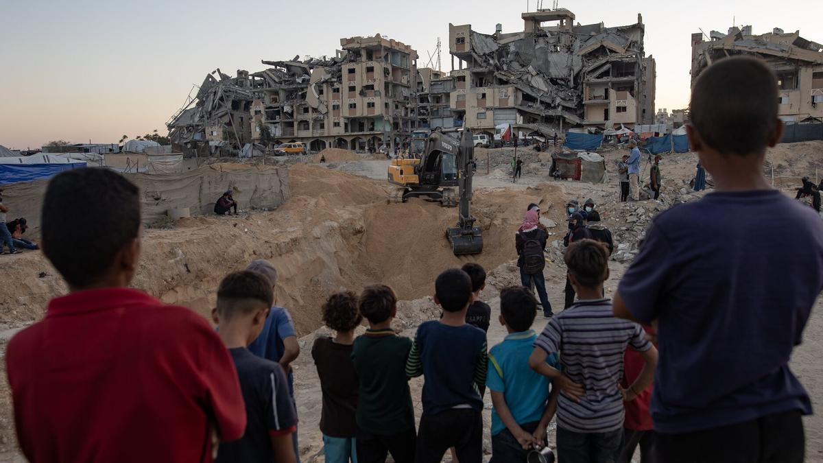 Niños palestinos observan el 27 de octubre los movimientos de una excavadora procedente de Egipto en un paraje arradado en Khan Yunis.