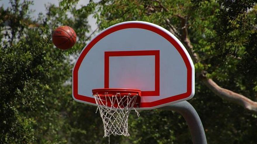 Foto de una pelota cerca de un aro de baloncesto.