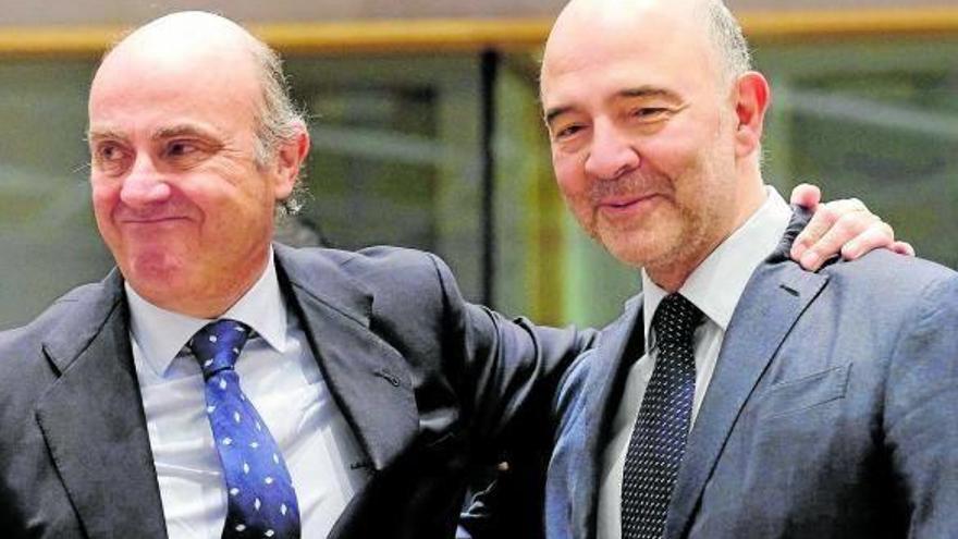 Luis de Guindos saluda al comisario europeo de Economía y Asuntos Financieros, Pierre Moscovici.