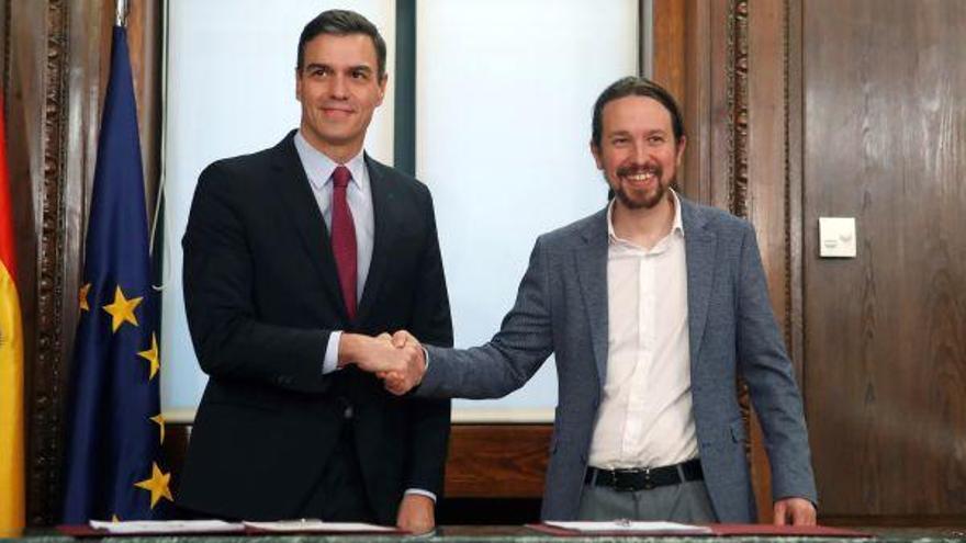 El candidato a la investidura, Pedro Sánchez, y el líder de Podemos, Pablo Iglesias, estrechan sus manos durante el acto de firma del acuerdo programático con las principales medidas que tomará el futuro Gobierno de coalición.