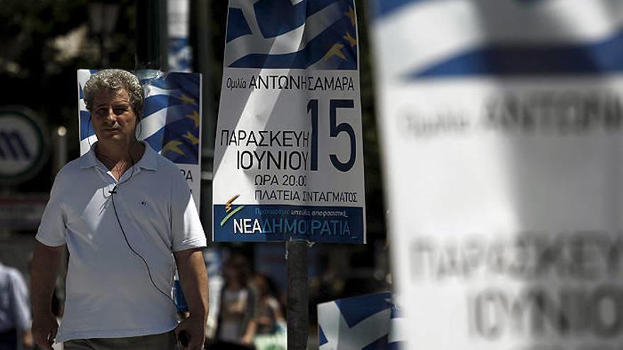 Un hombre camina junto a varios carteles del partido conservador griego Nueva Democracia (ND), en Atenas, Grecia.