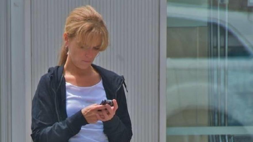 Una mujer camina mientras mira su teléfono móvil.