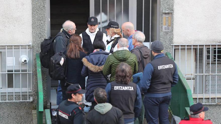 Vecinos y familiares conversan en el portal de las víctimas con agentes de la Ertzaintza.