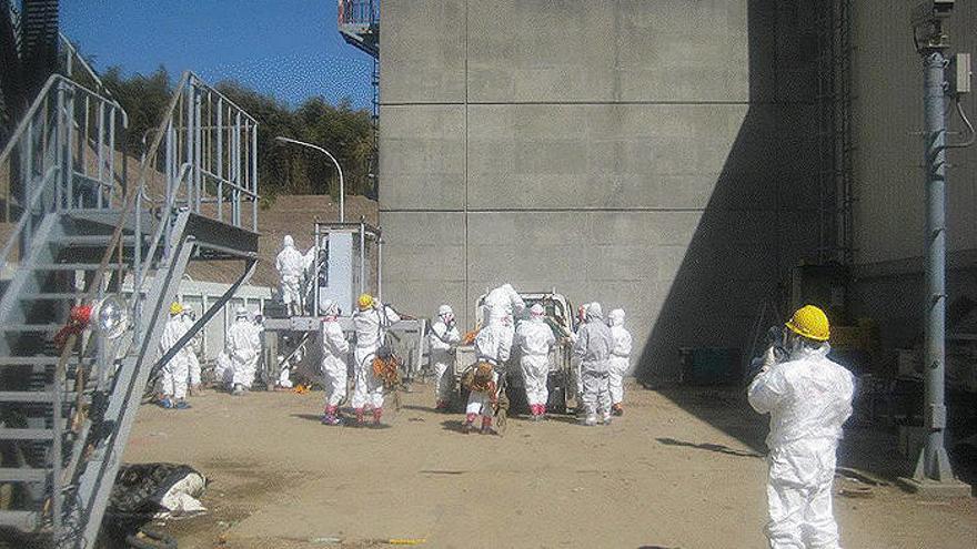 Fotografía facilitada por la empresa operadora de la central nuclear de Fukushima Daiichi, TEPCO, que muestra a sus trabajadores vestidos con monos especiales mientras trabajan en reestablecer el tendido eléctrico en los reactors 3 y 4 de la planta, en Ok