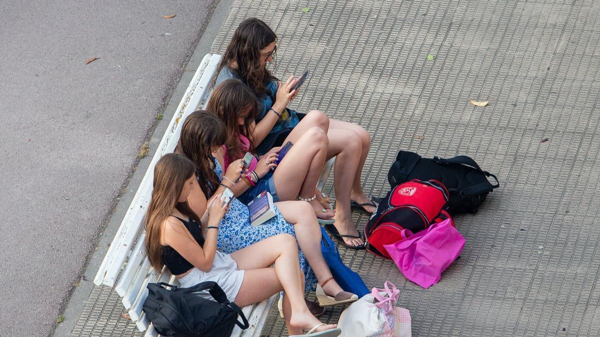 Cuatro jóvenes sentadas con sus teléfonos móviles