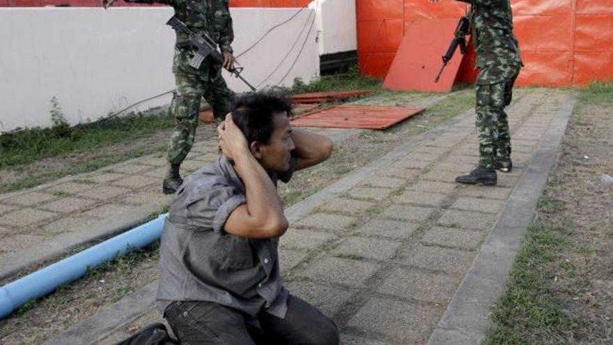 Soldados tailandeses detienen a un seguidor del Gobierno, varios de cuyos miembros fueron también detenidos.