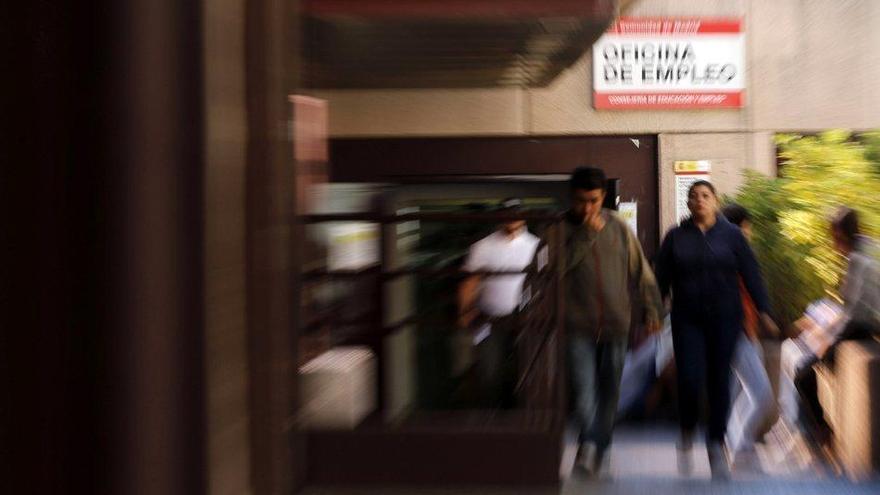 Varias personas saliendo de una oficina de empleo.