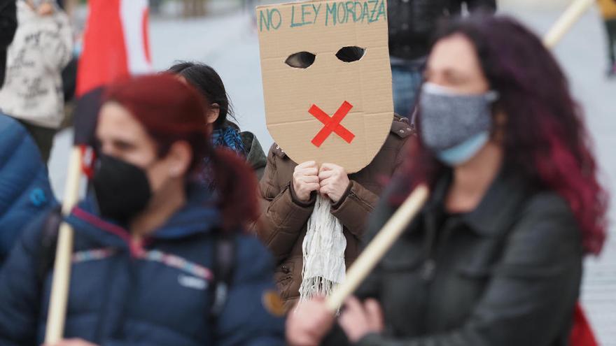 Una persona sostiene una careta donde se lee &quot;No Ley Mordaza&quot; durante una manifestación.