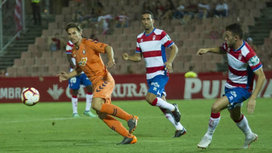 En la imagen, Xisco intenta llegar a un balón, perseguido por dos rivales, ante una grada semidesierta. Foto: Agencia LOF