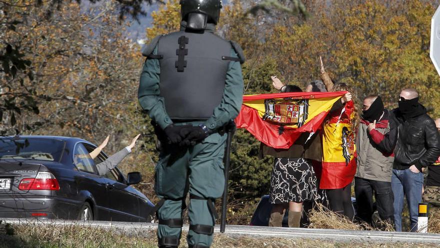 Un miembro de la Guardia Civil observa como un grupo de partidarios de Franco saluda a un coche de simpatizantes durante la concentración.