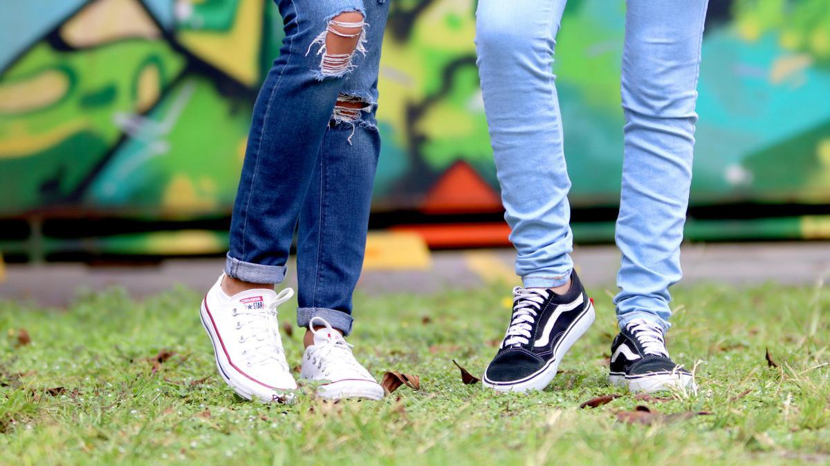 Plano detalle de las piernas de dos jóvenes mientran conversan.