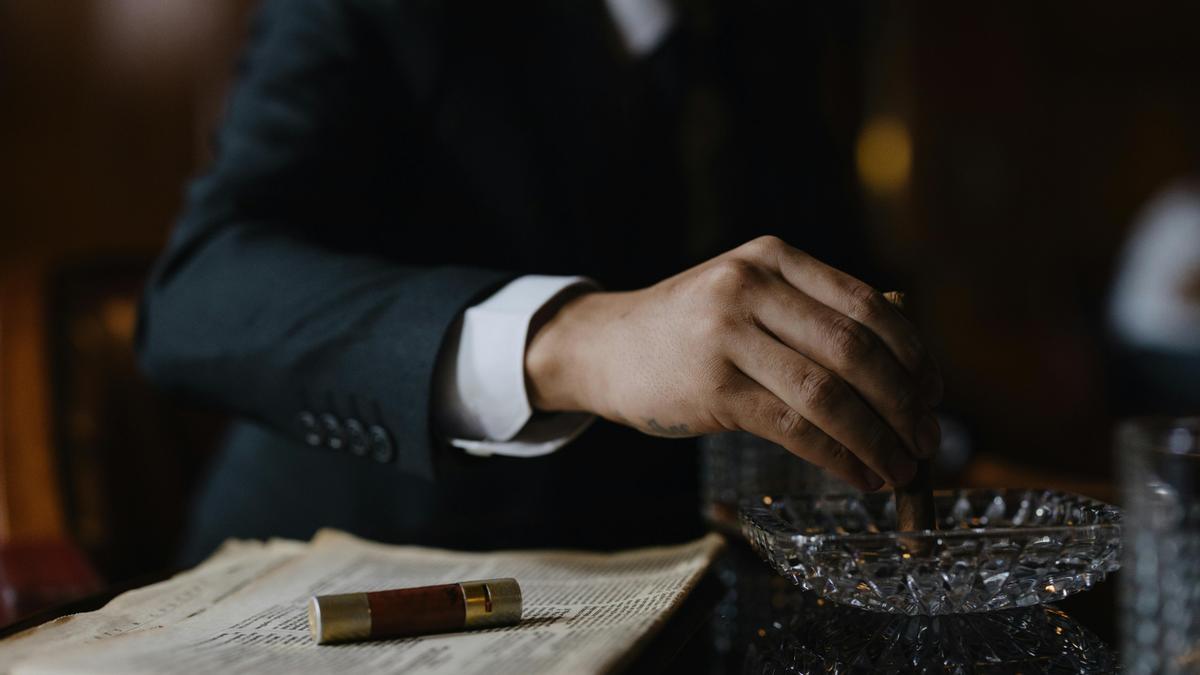 Un hombre en traje apagando un cigarro.