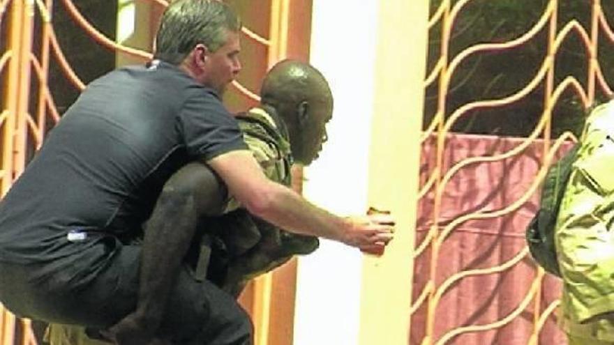 Dembélé lleva sobre su espalda, fuera del hotel atacado, a un ciudadano occidental.