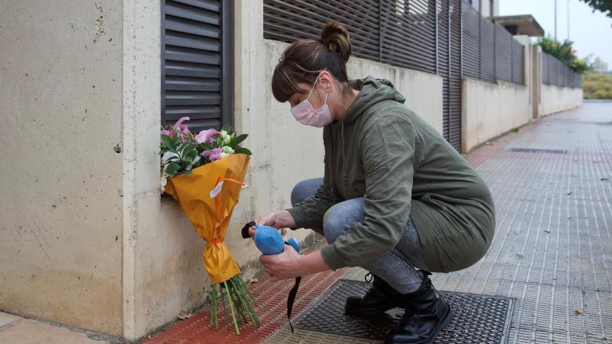 Una mujer coloca flores en el portal en el que fue hallado el niño