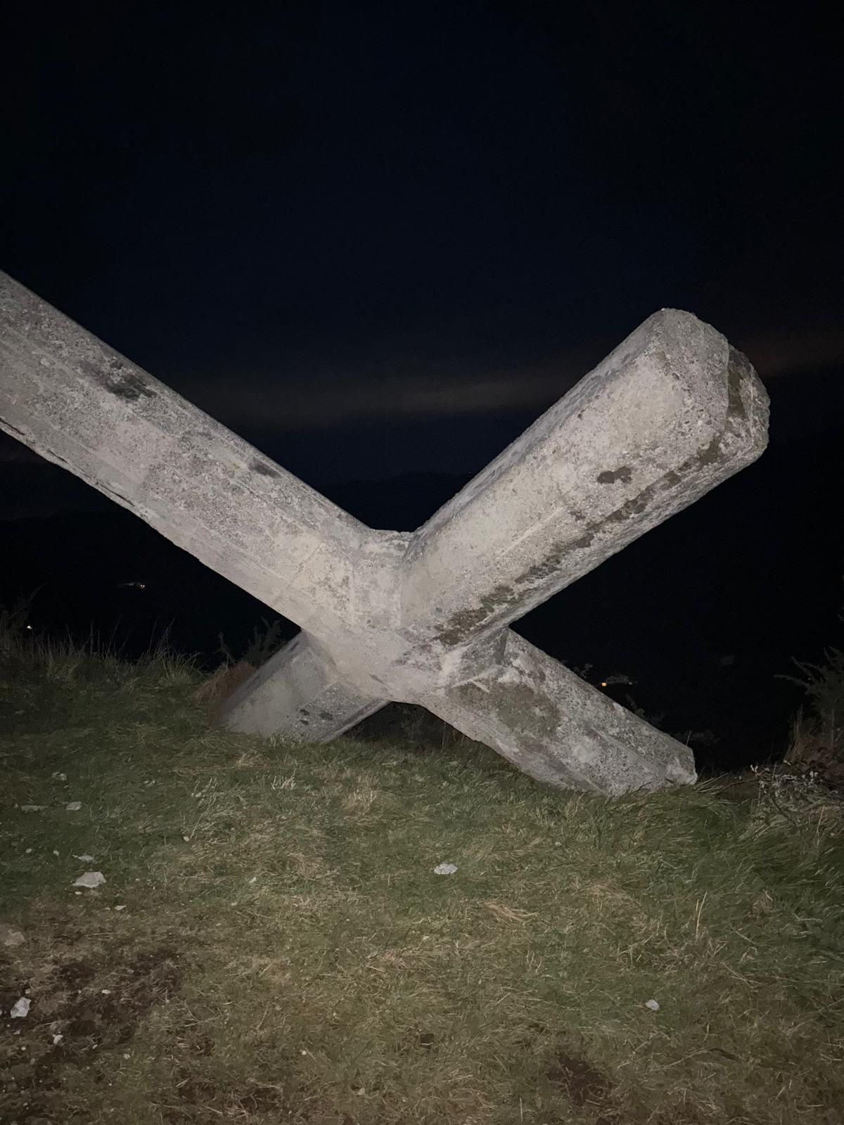 La cruz yace sobre el suelo, apoyada en parte en el pedestal.