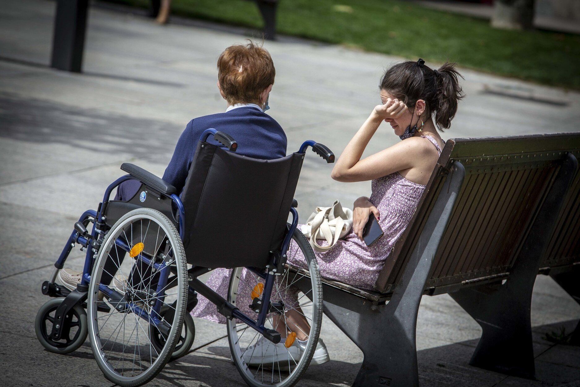 Una persona mayor en silla de ruedas, junto a una persona acompañante, en una imagen de archivo.