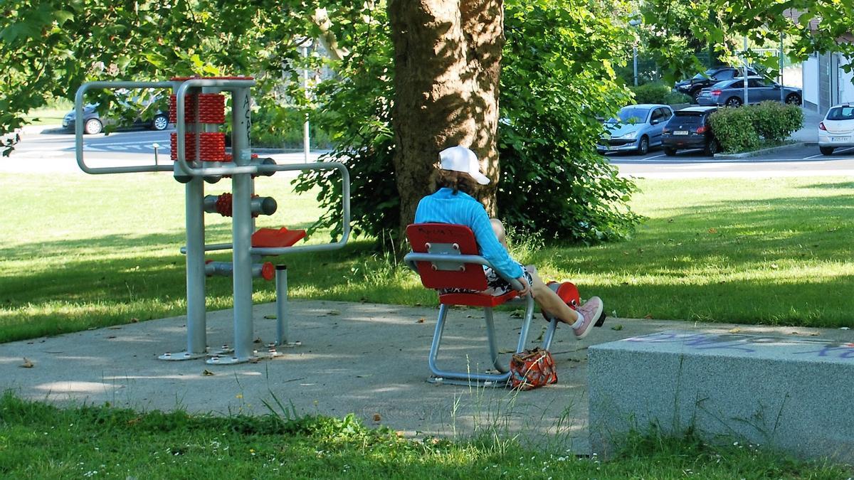 Una mujer mayor hace ejercicio en uno de los aparatos de gimnasia instalados en el parque de la calle Intxaurdui, junto al club de jubilados y la residencia