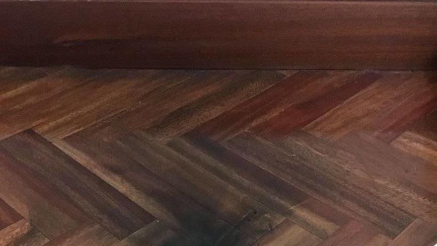 El móvil que sufrió la deflagración junto al suelo ennegrecido de la habitación.