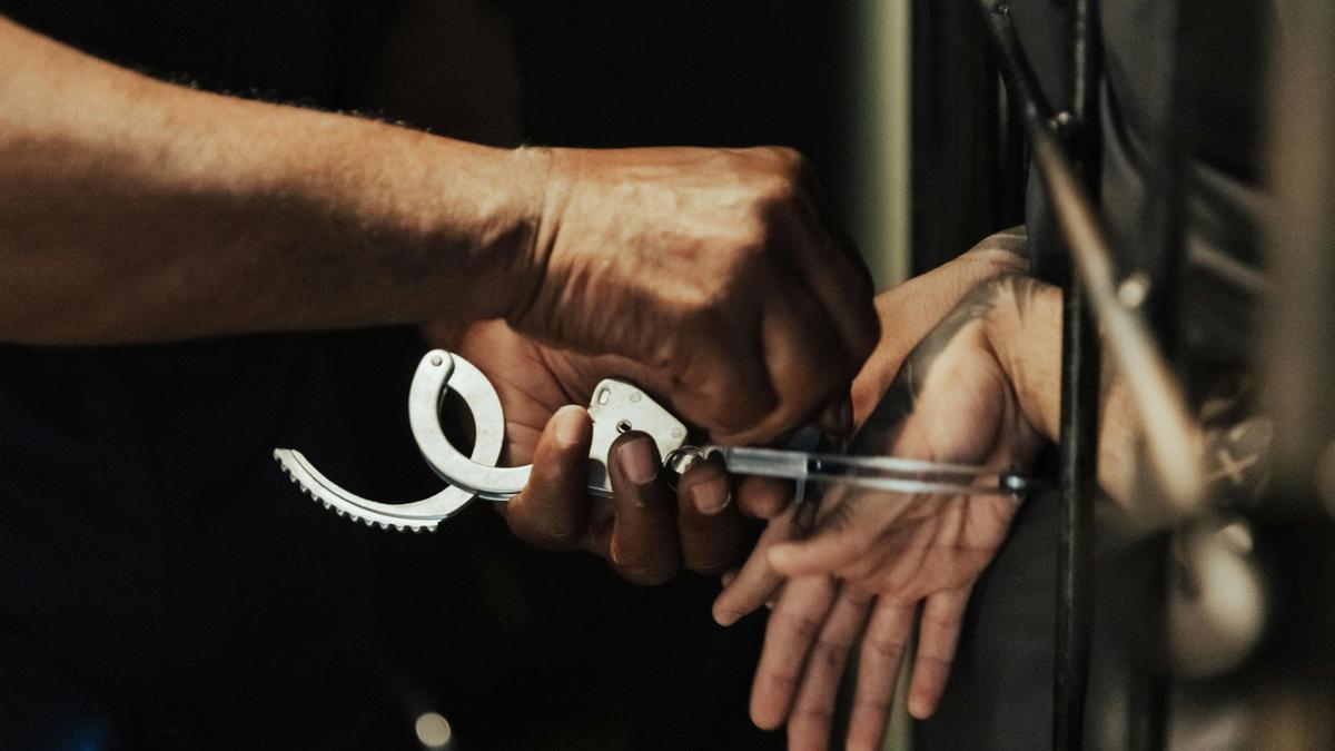 Una persona quitandoles las esposas a un prisionero.
