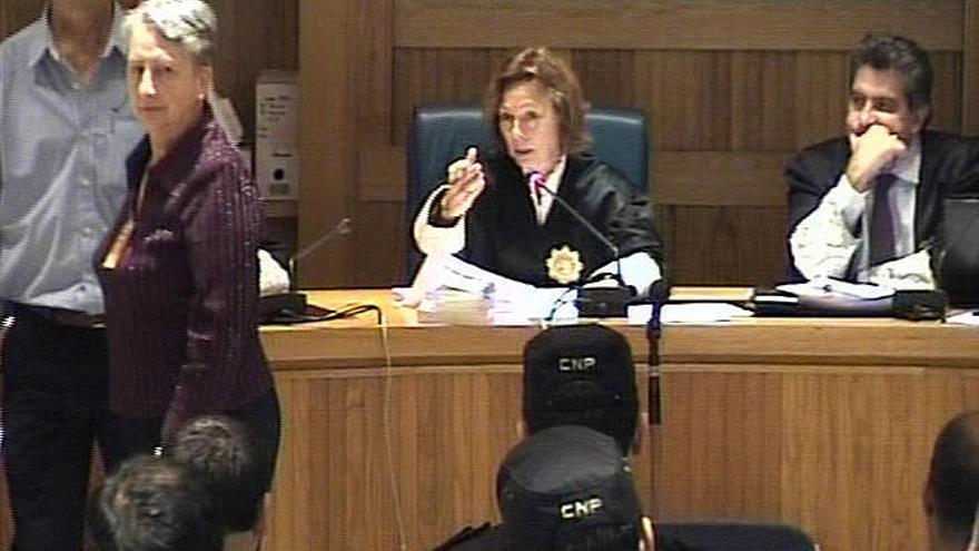 Imagen capturada del vídeo de señal institucional grabada por la Audiencia Nacional de Adoración Zubeldia (izda.), viuda del concejal de UPN en Leiza José Javier Múgica, asesinado por ETA en 2001, con la vista buscando los ojos de los acusados, que no han