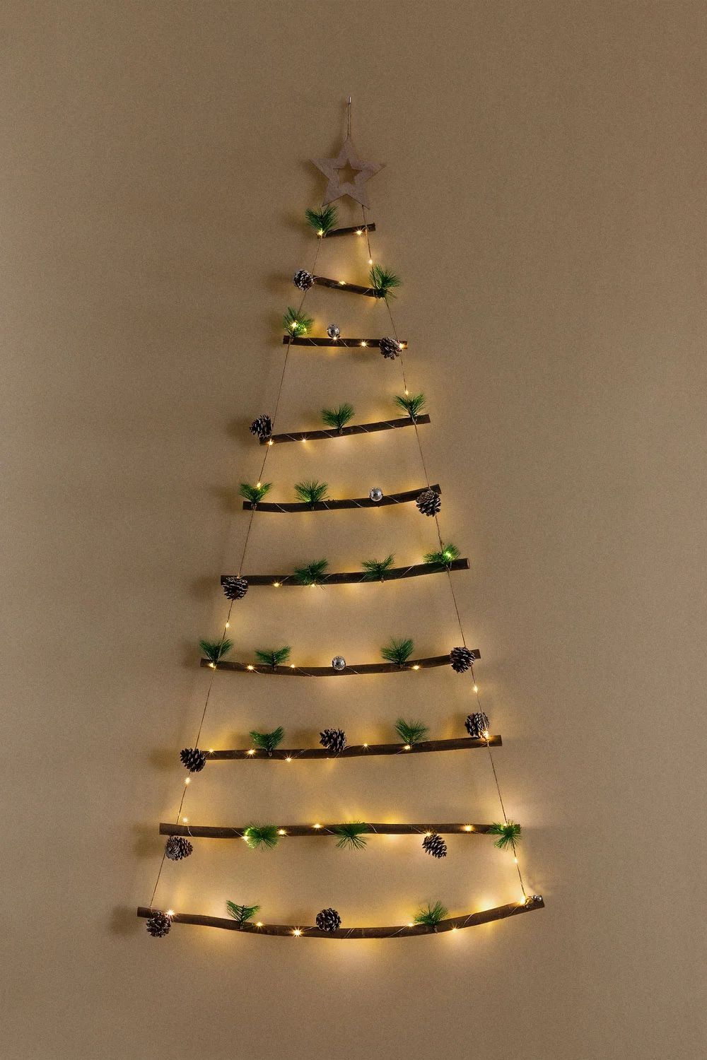 Bonito árbol de Navidad de pared formado por ramas, cuerdas y luces.