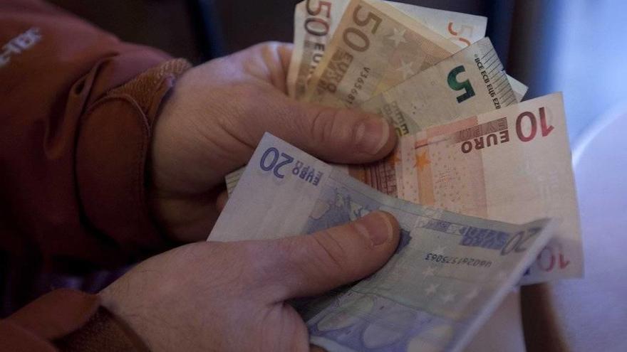 Una persona cuenta cuántos euros tiene en billetes.