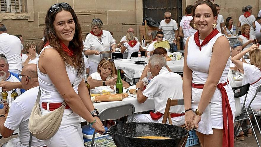 Dos sesmeras llevando la perola llena de pochas a la mesa de su cuadrilla.