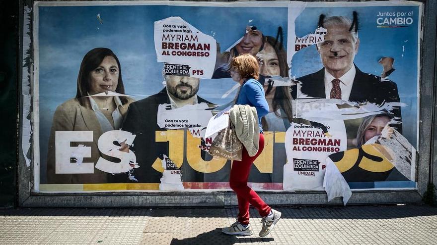 Una mujer ante un cartel con publicidad electoral en Buenos Aires