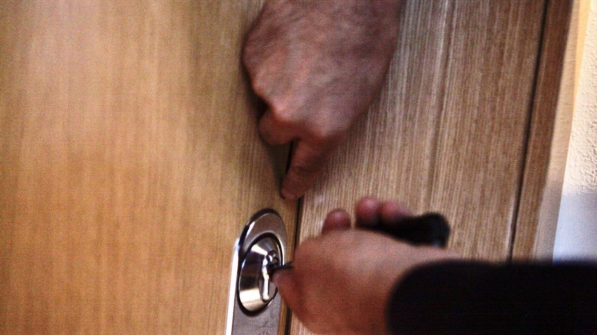 Imagen de archivo de una persona forzando una puerta. Imagen de archivo de una persona forzando una puerta.