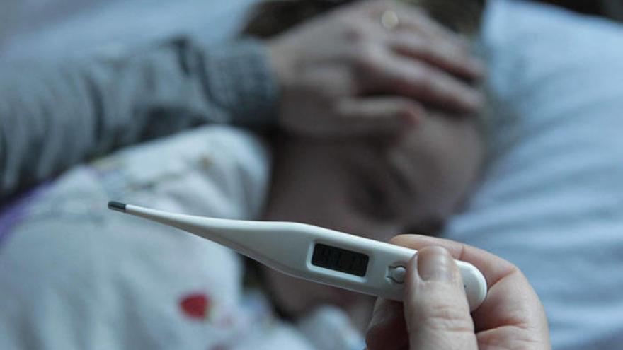 Un termómetro indicando fiebre alta en una niña con gripe.