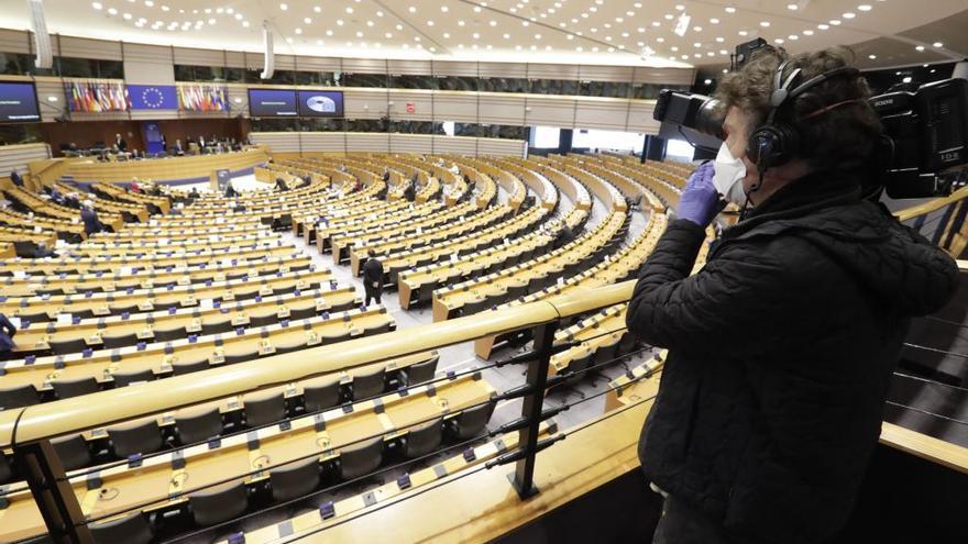 Una periodista con mascarilla por el coronavirus escuchando la reunión del pleno del Parlamento.