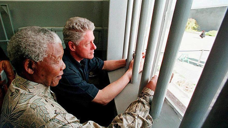 Fotografía de archivo del 27 de marzo de 1998 del Premio Nobel de Paz sudafricano Nelson Mandela (i) junto al expresidente estadounidense Bill Clinton (d), en una celda en la cárcel en donde Mandela pasó 18 de sus 27 años como prisionero político en Robbe