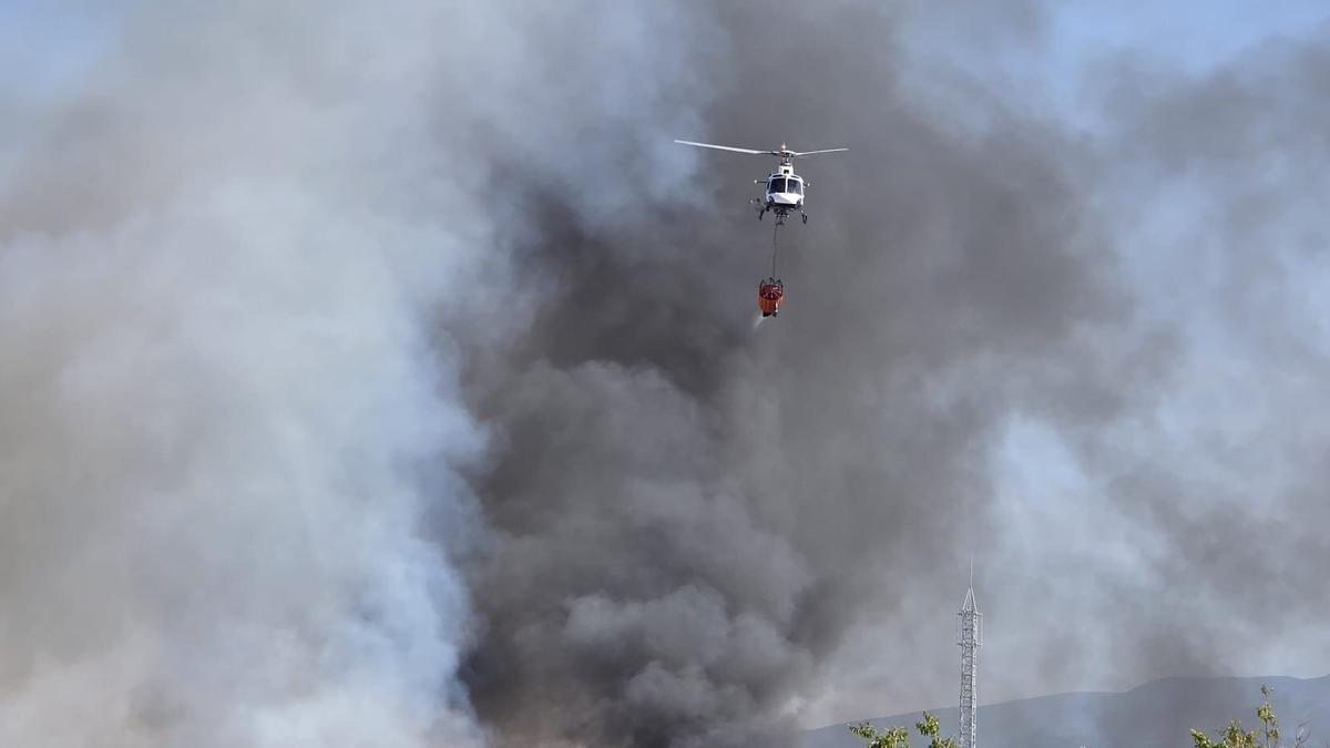 Un helicóptero tras soltar agua en la zona del incendio.