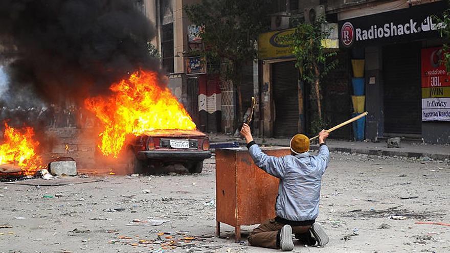 Un manifestante, parapetado tras un mueble, provoca a la policía durante los incidentes en las proximidades de la Plaza Tahrir, en El Cairo, Egipto.