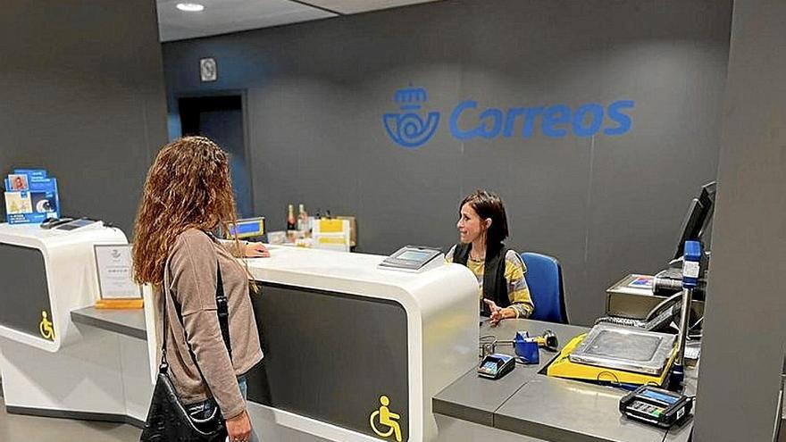 Una mujer es atendida en una oficina de Correos.