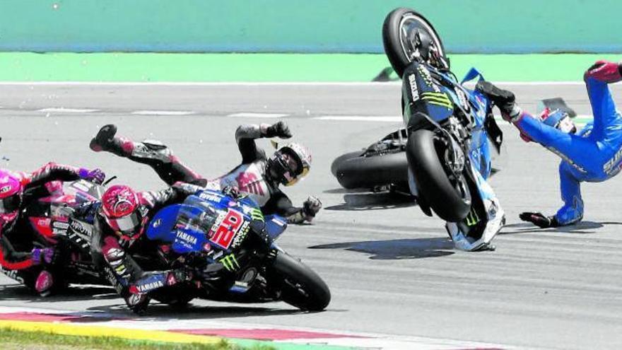 Instante de la caída de Nakagami, Rins y Bagnaia, que llega por detrás, en el paso por la primera curva de la carrera, con Quartararo y Aleix Espargaró saliendo indemnes. Foto: Efe