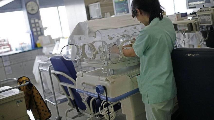 Una enfermera vigila a un bebé prematuro que permanece en incubadora.