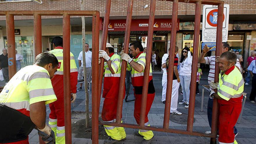 Operarios de Arganda del Rey (Madrid) retiran una valla del recorrido del encierro.