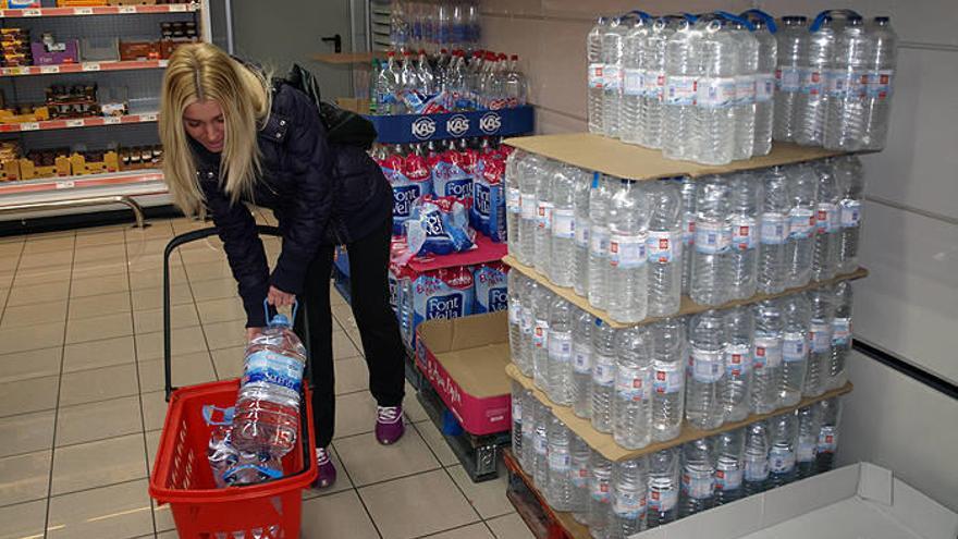 Una mujer introduce en su carro garrafas de agua en un supermercado de Alsasua.