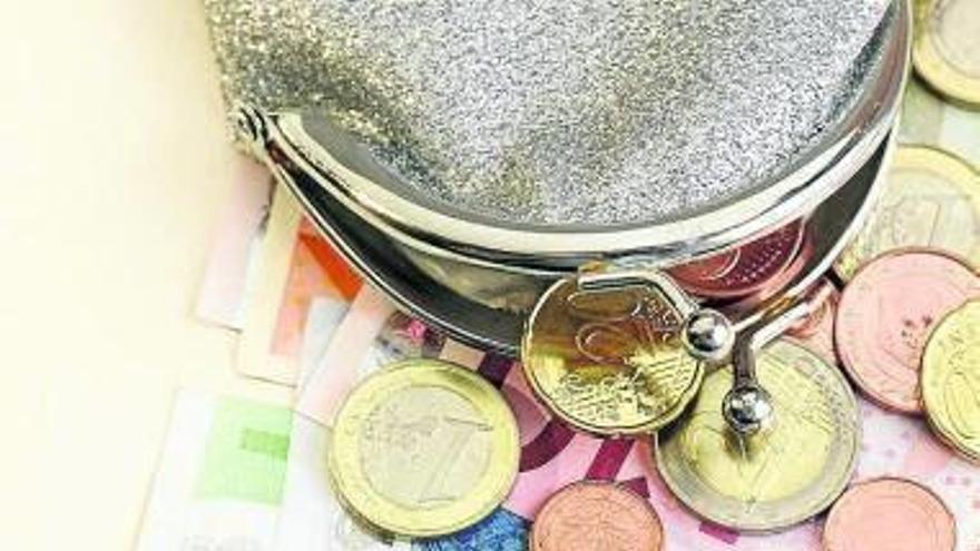 Una cartera abierta junto a monedas y billetes de euro.