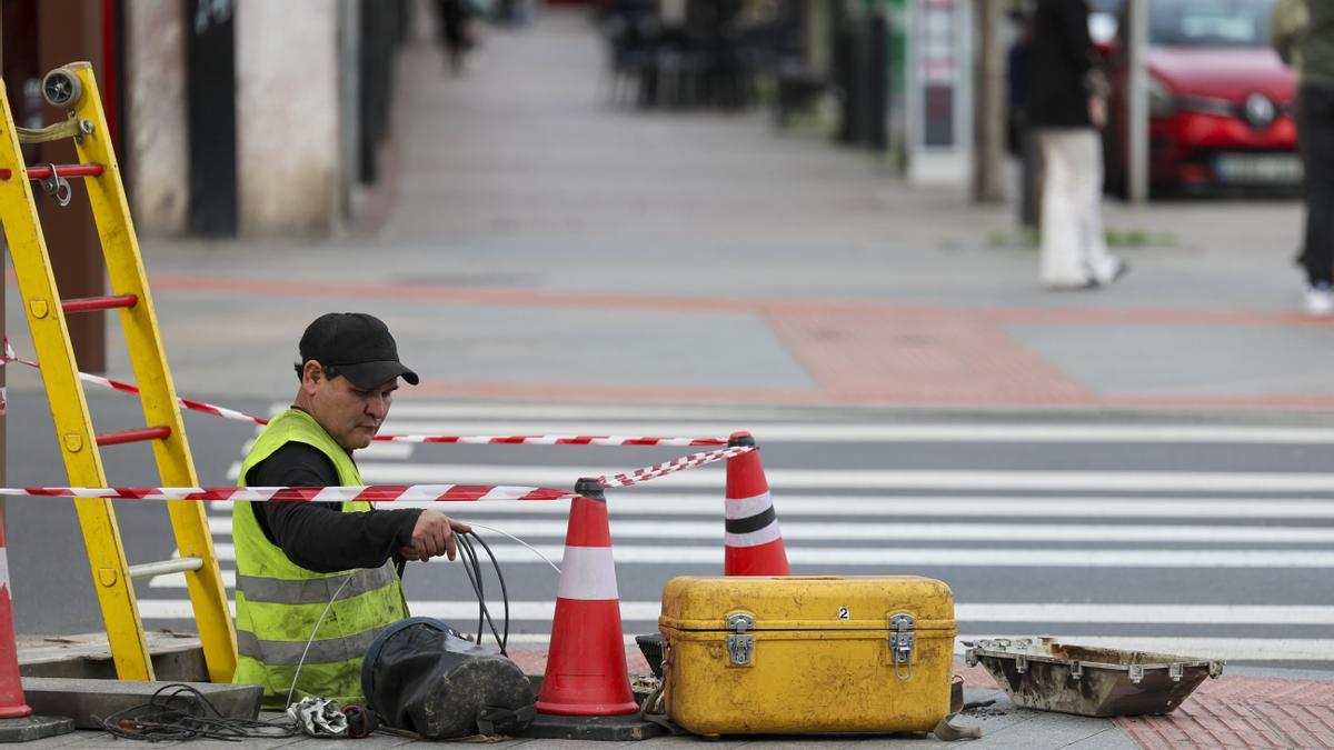 Un trabajador tiende cable en una calle.