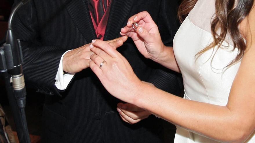 Una pareja intercambia sus alianzas en una boda civil.