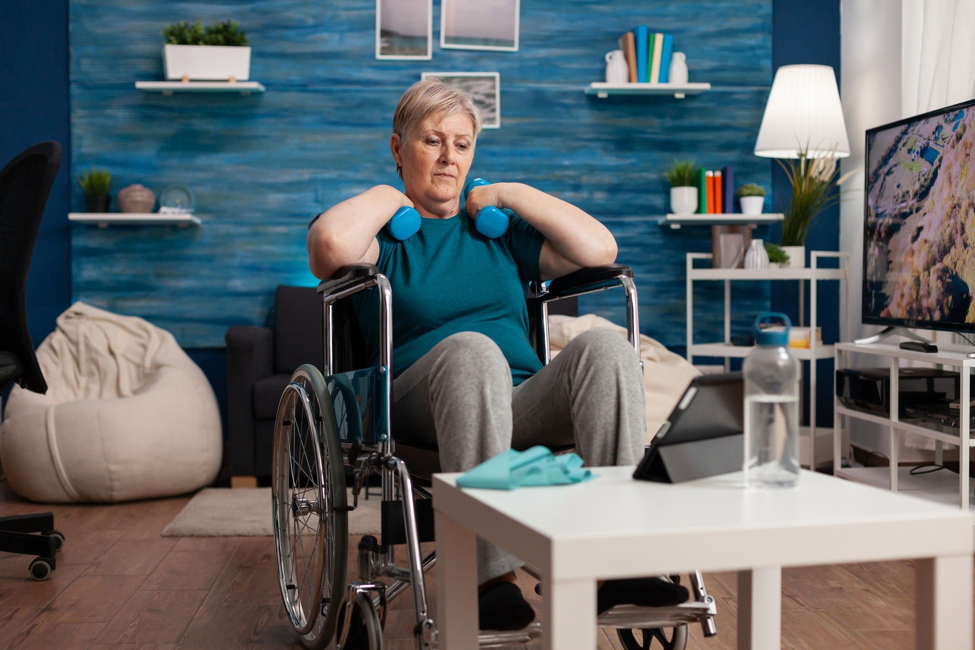 Una mujer sentada en una silla de ruedas por una dolencia hace rehabilitación.