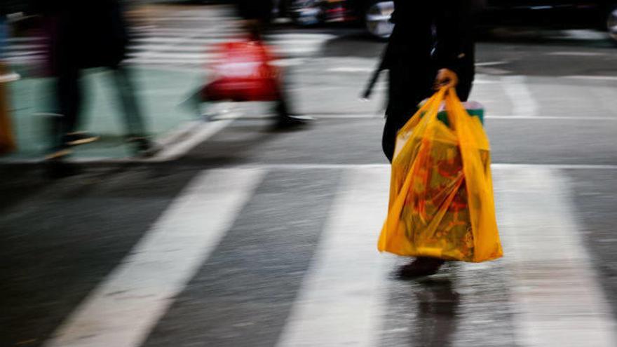 Una persona cruza una calle con una bolsa de plástico.