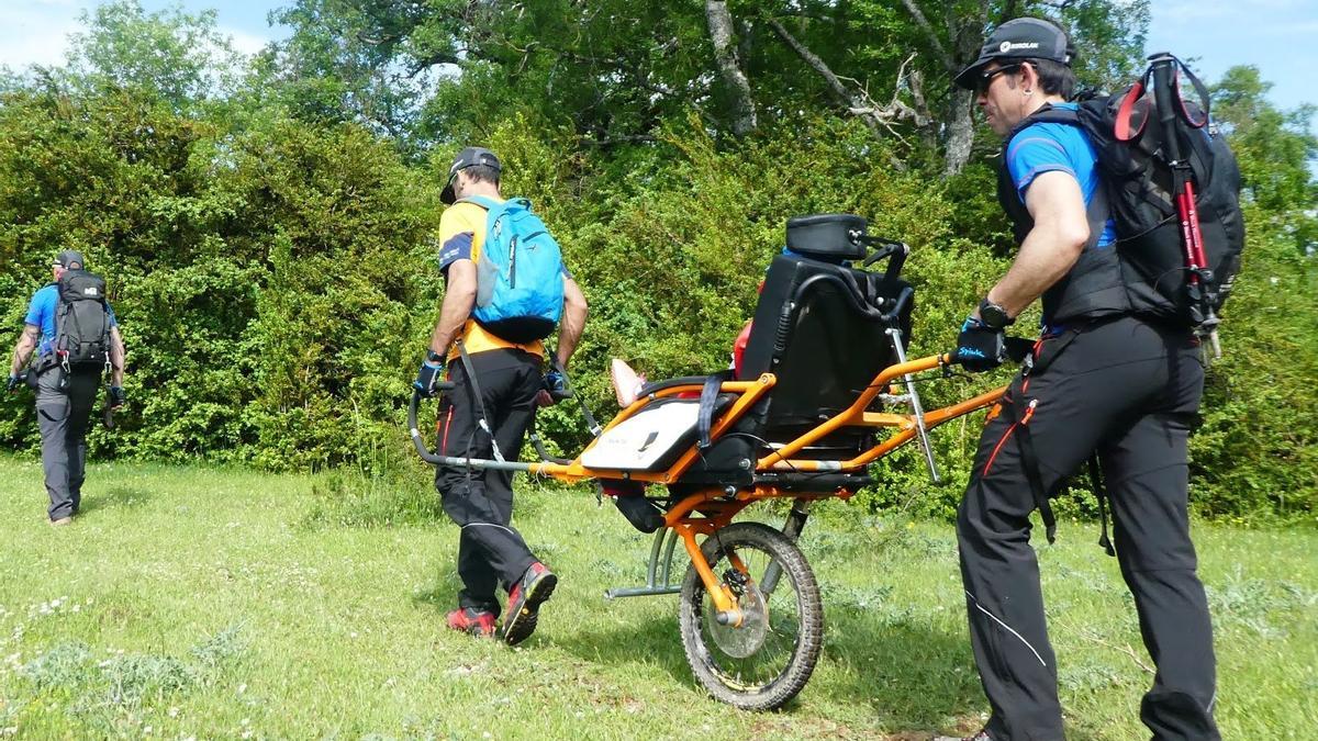 Miembros del colectivo Montes Solidarios durante una salida al monte con una persona con movilidad reducida
