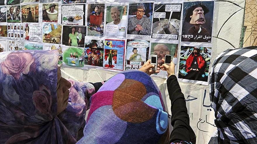 Mujeres libias toman fotografías de una pared con caricaturas del fugitivo líder libio Muamar El Gadafi en la plaza Martyr (antes la plaza Verde) en Trípoli, Libia.