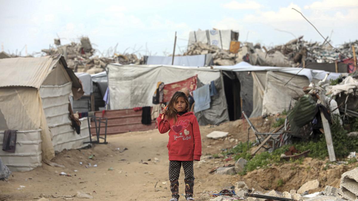 Una niña palestina es fotografiada cerca de una tienda de campaña entre casas destruidas en el norte de la Franja de Gaza.