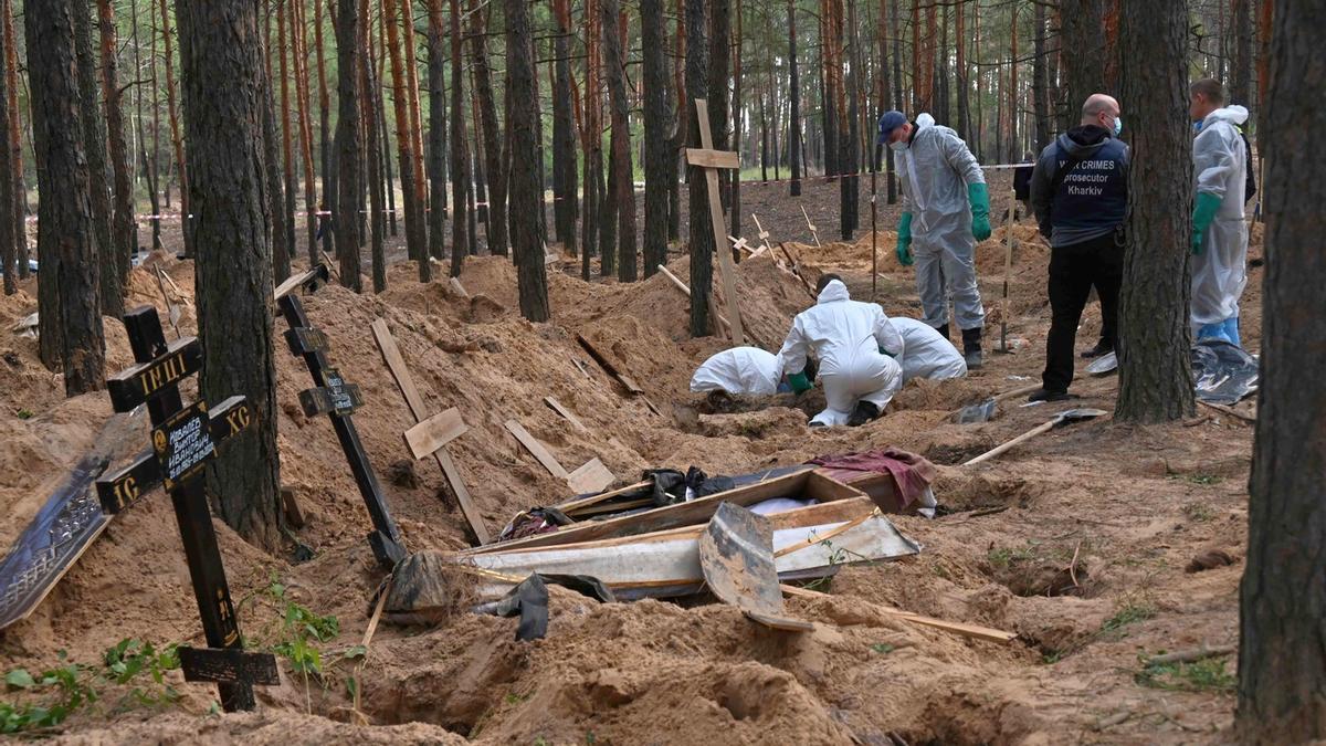 Forenses y oficiales exhuman los cuerpos de civiles y militares hallados en 445 tumbas en la localidad de Izium.